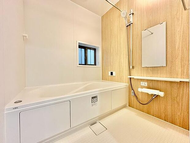 清潔感のあるバスルームです。木目調の壁面が空間に温かみを与えています。大きな浴槽でゆったり過ごせます。窓があり換気もしやすいです。浴室乾燥機付きで機能性にも配慮されています。