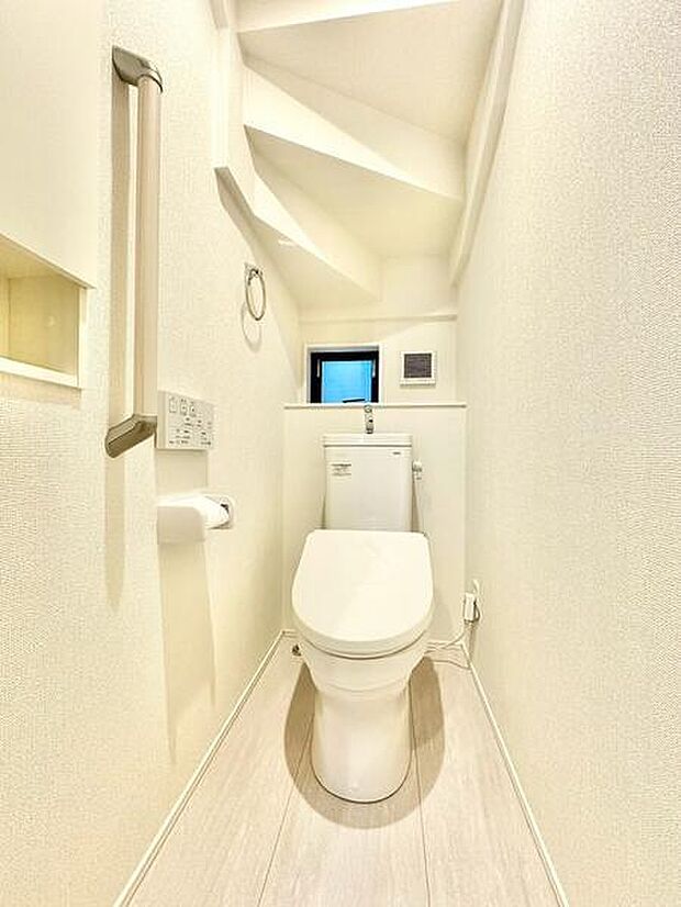 手すり付きのトイレ。ご高齢の方も安全に利用できます。ニッチ棚は、収納や飾り棚として活用でき、すっきりとした空間を演出します。