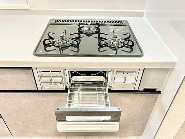 三口コンロとグリルを備えた機能的なキッチン。広々とした作業スペースを確保し、毎日の料理を快適にサポートします。