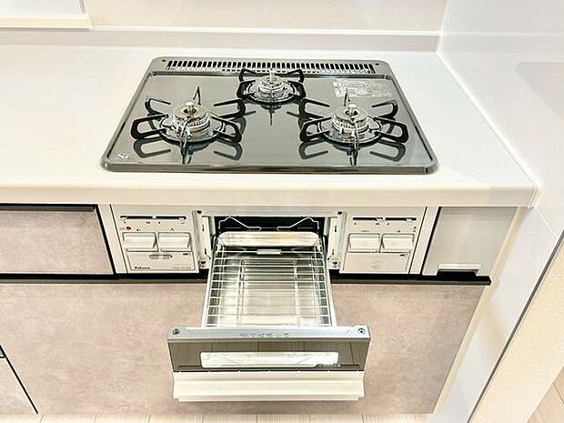 三口コンロとグリルを備えた機能的なキッチン。広々とした作業スペースを確保し、毎日の料理を快適にサポートします。