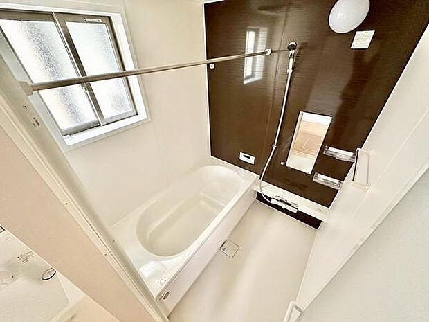 落ち着いた色合いのバスルームで、窓から自然光が入り明るさを感じられます。ゆとりある浴槽でゆったりくつろげ、壁面デザインがアクセントとなった清潔感のある空間です。