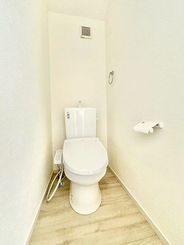 トイレは温水洗浄便座付きです。タオル掛けとペーパーホルダーが設置されており、落ち着いた色合いでまとめられた水回りです。