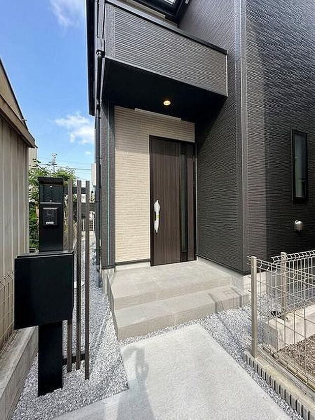 石張り調のアプローチ階段が玄関まで続くエントランス。ポストとモニター付きインターホンを設置しており、宅配や来客への対応がスムーズに行える動線が整っています。