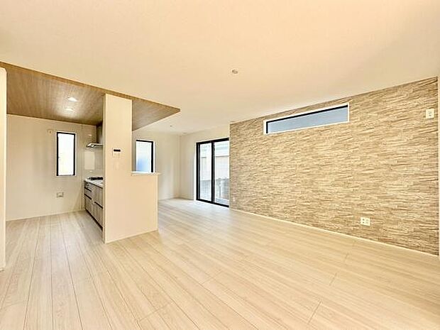 【17帖】リビングは優しい色合いのフローリングが広がり開放的な空間です。キッチンとの繋がりも良く窓からの採光が明るさを演出しています。アクセントウォールが印象的なデザインです。