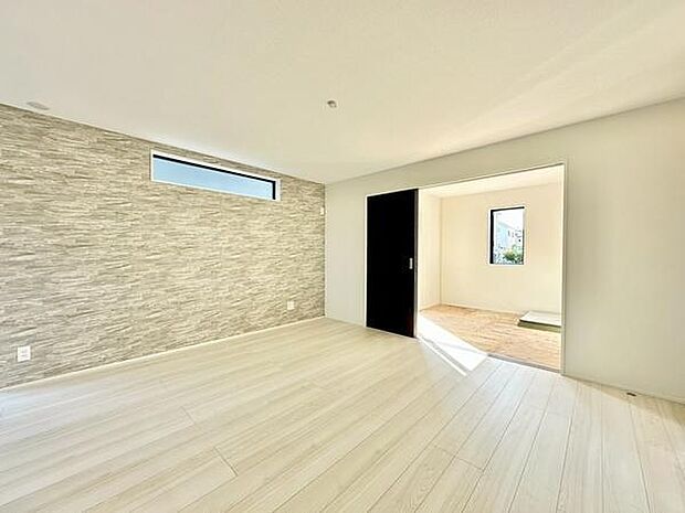 【17帖】明るい採光が魅力のリビングです。床や壁のデザインが空間をすっきりと見せています。隣接した洋室への動線がスムーズです。広々とした空間で家具の配置にも困りません。