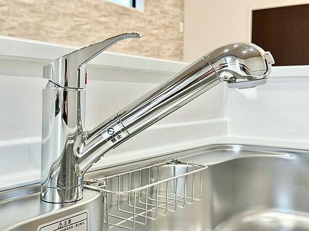 キッチンに備え付けられた水栓はシンプルで使いやすいデザインです。鏡面仕上げが清潔感を演出しています。シンクの形状も工夫されており作業がしやすい印象です。収納ラックが付いており小物の整理に便利です。