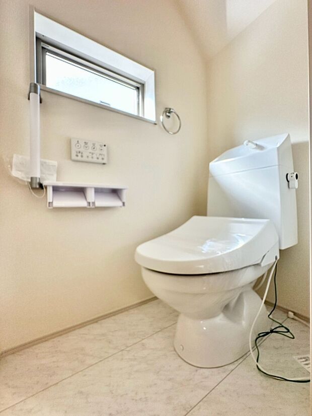 明るい日差しが入る窓付きのトイレです。壁面にリモコン操作パネルが設置されておりすっきりとした印象です。コンパクトな空間でも快適にお使いいただけます。