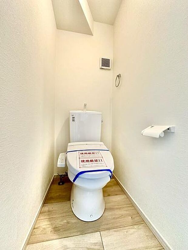 清潔感のある明るいトイレ空間。床材のデザインが引き締め効果を与え、ホワイトで統一された壁が圧迫感を感じさせません。ペーパーホルダーやタオルリングなど設備も充実しています。