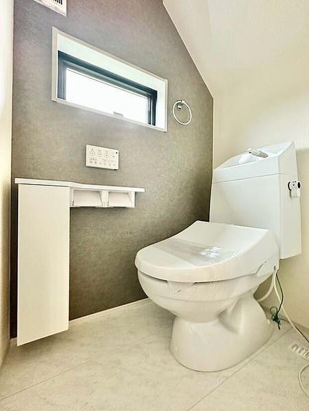 グレーのアクセントウォールを取り入れた、落ち着いた印象のトイレ。トイレットペーパーロールを2つ設置でき、使い勝手にも配慮されています。