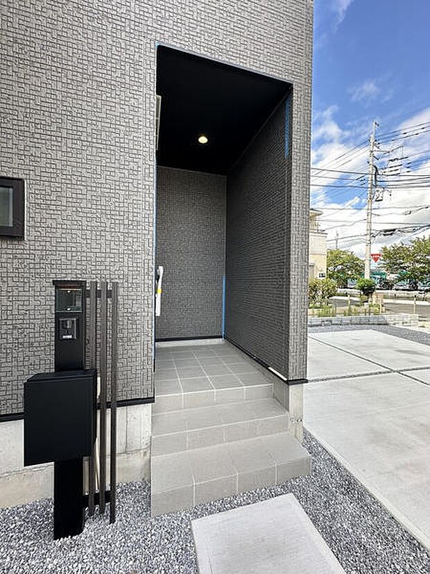 壁に囲まれた玄関アプローチは、雨の日の出入りにも嬉しい設計。L字の動線が外からの視線を遮り、プライバシーにも配慮されています。