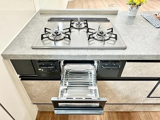 3口ガスコンロとグリルを備えた使い勝手の良いキッチン。お手入れしやすい天板を採用し、収納スペースも充実しています。