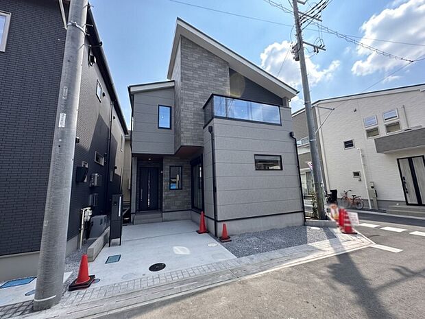 石目調の外壁が重厚感を演出するエントランス。天井の木目デザインが温かみを添え、広めの玄関ポーチとスタイリッシュな玄関ドアが上質な印象を与えます。