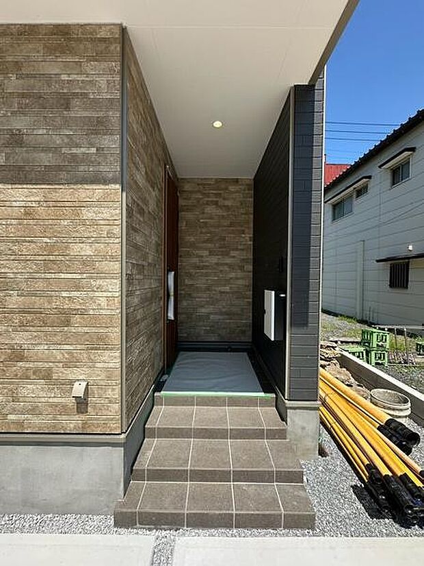 L字型のアプローチを採用した玄関まわり。道路から玄関までの視線が入りにくく、プライバシーにも配慮された落ち着きのある設計です。