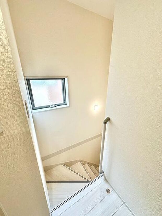 窓を設けた明るい階段スペース。手すりも備えており、上り下りの際にも使いやすい仕様です。家族が安心して利用できます。