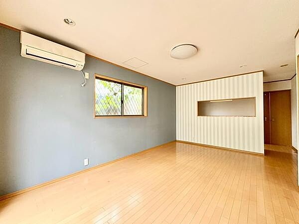 アクセントクロスとストライプ柄の壁が印象的な、明るく爽やかなリビング空間。落ち着いた色合いが木目の床と調和し、心地よい雰囲気を演出しています。