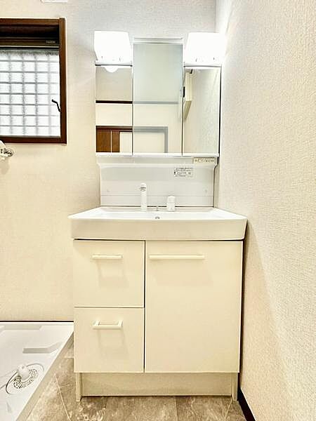 白を基調とした明るく清潔感のある洗面台。三面鏡付きで、毎日の身だしなみチェックもしやすい使い勝手の良い洗面スペースです。