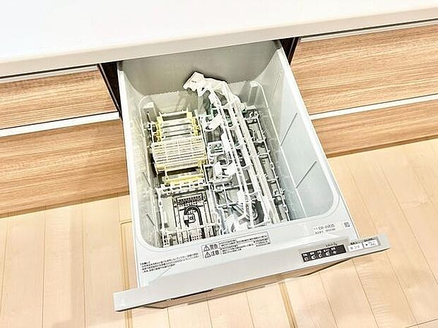キッチンにビルトインタイプの食器洗浄機が設置されています。調理後の食器も手軽に片付けが可能です。設備が整った空間で日々の家事をサポートします。木目調の収納と調和したデザインです。