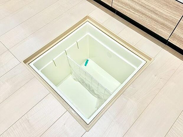 キッチンの床下収納が設置されており整理しやすいスペースが確保されています。清潔感のある内装と明るい色合いの床が特徴です。収納部分は取り出しやすい仕様になっています。日常の整理に役立ちます。