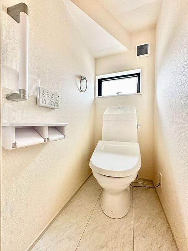 清潔感のある明るいトイレです。窓付きで換気もしやすいです。シンプルなデザインでお手入れも簡単です。ペーパーホルダーや手すりが設置されていて便利です。