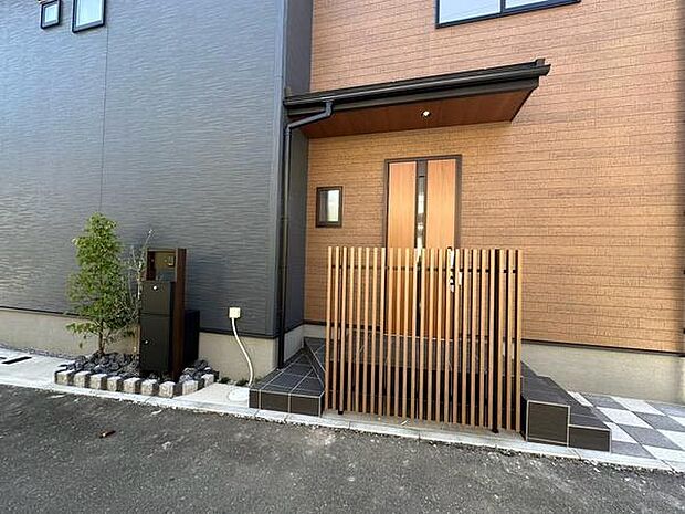 玄関の左右に階段を設けた、動線にも配慮されたアプローチ。縦格子を取り入れることで、デザイン性を高めながら外からの視線にも配慮した玄関まわりです。