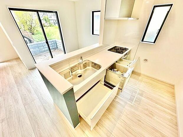 明るい光が差し込むキッチンは清潔感のある空間です。引き出し収納が充実しており調理器具の整理がしやすい設計です。シンクとコンロが近く効率的な動線が魅力です。窓が多く換気がしやすい点もポイントです。