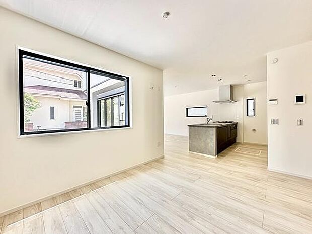 リビングには大きな窓があり明るい陽射しが差し込みます。キッチンまで見渡せる開放的な空間です。床材は落ち着いた色合いで清潔感が感じられます。すっきりとしたデザインが特徴です。