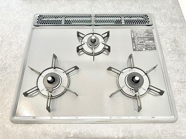 3口のガスコンロが設置されており複数の調理に対応できます。フラットな天板なので日々のお手入れも簡単です。シンプルなデザインで空間に調和しやすいキッチン設備です。操作部分も見やすく配置されています。