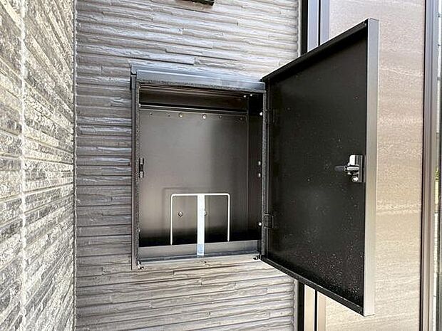 壁面に設置された宅配ボックスです。扉がしっかりと閉まる構造で内部もシンプルなデザインです。外観の雰囲気にも調和しています。荷物の受け取りにも便利です。雨風にも配慮された設計です。