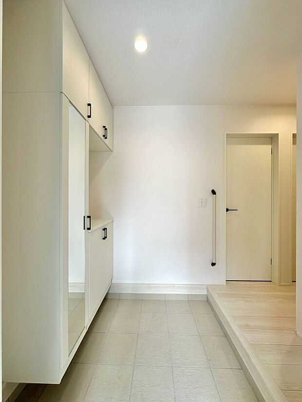 ナチュラルな木目と白色の扉が調和し明るい玄関の清潔感を演出します。大型のミラー付きで外出前の身だしなみも整えやすいです。