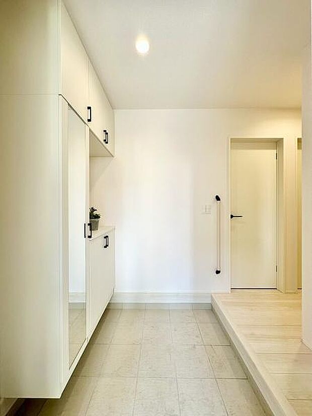 ナチュラルな木目と白色の扉が調和し明るい玄関の清潔感を演出します。大型のミラー付きで外出前の身だしなみも整えやすいです。