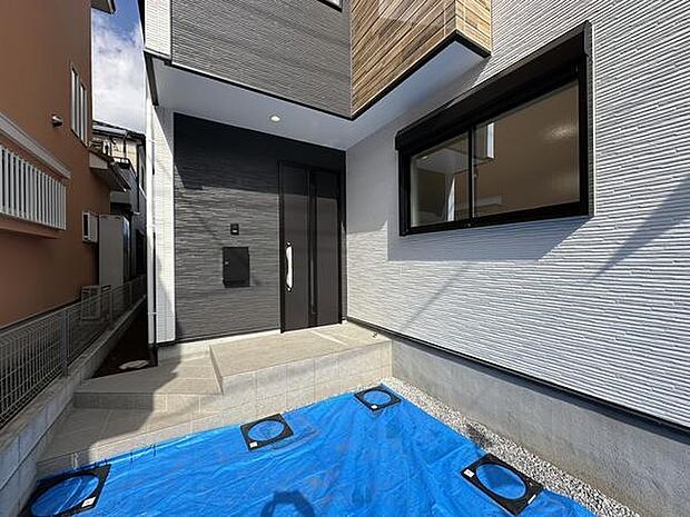 スタイリッシュな玄関扉が印象的な空間です。タイル張りの壁面が上品な雰囲気を演出します。雨の日でも安心なタイルフロアです。スッキリとしたデザインで清潔感があります。