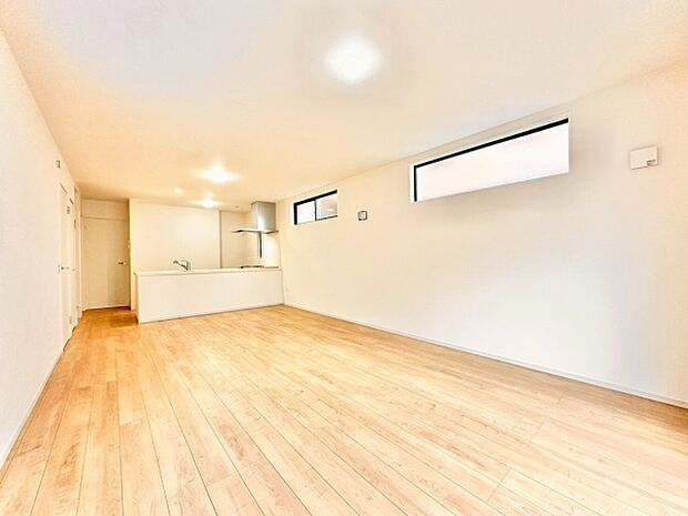 【18.7帖】明るい色合いのフローリングが空間を広く見せます。縦長の窓が採光にも配慮されています。シンプルな内装で様々なインテリアに合わせやすいリビングです。キッチンとの一体感ある設計が特徴です。