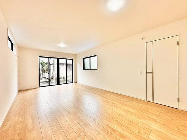 【18.7帖】大きな窓から自然光がたっぷり差し込むリビングです。シンプルな内装が開放感を引き立てています。床材の温かみが空間を優しくまとめています。ドアや窓の配置が機能的です。