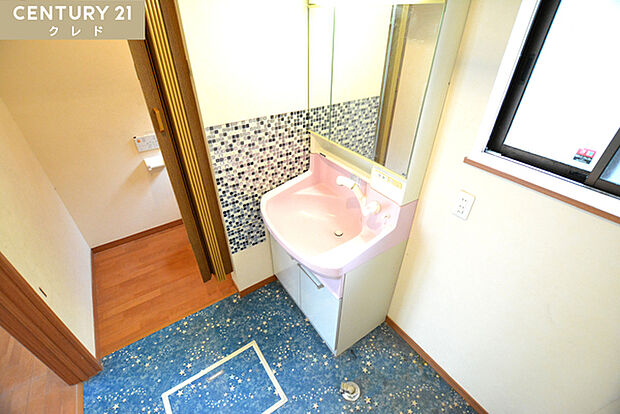 ブルーモザイクタイルの壁と星柄の床がオシャレな洗面室！ピンクの可愛らしい三面鏡付洗面化粧台完備！鏡裏に小物を収納できるスペースがあります！オシャレなだけではなく機能的だと嬉しいですね！
