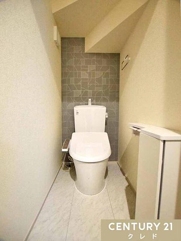 肌への負担に配慮し、快適な生活をサポートする温水洗浄トイレ。落ち着いたグレーのアクセントクロスが目を引く、デザイン性の高いトイレスペース。