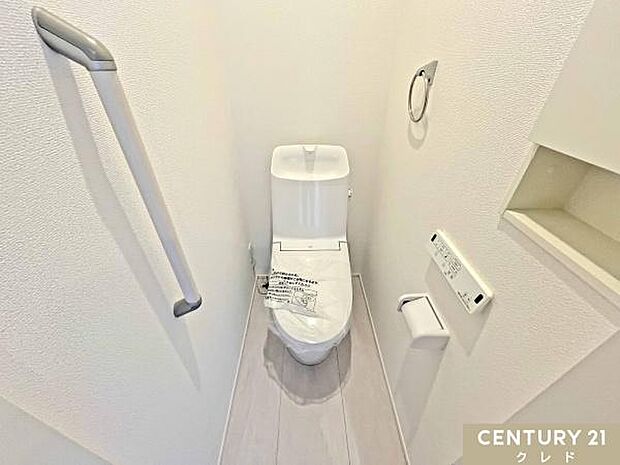 肌への負担に配慮し、快適な生活をサポートする温水洗浄機能付きトイレ。バリアフリーに配慮した手すり、壁面収納も備えた機能的な空間。