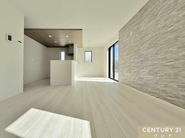 【LDK16.75帖】ストーン調のアクセントクロスやキッチン折り下げ天井の木の風合いがマッチしたメリハリのある16.75帖のリビング。テーブルやソファなどを、動線を確保した配置が可能。