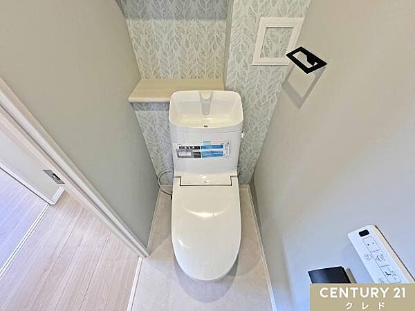 爽やかなリーフ柄のクロスが印象的な清潔感のあるトイレに新規交換。背面には収納に便利な棚を完備しており、トイレットペーパーや小物をすっきり整理できます。