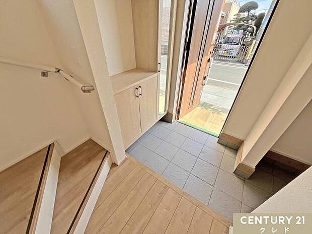 ナチュラルな木目とグレーのタイルが調和した、清潔感あふれる玄関スペース。収納力のあるシューズボックスには姿見が付いており、お出かけ前の身だしなみチェックに便利です。