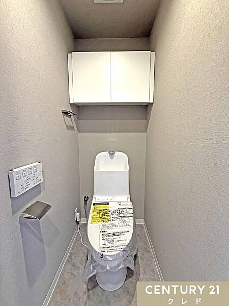 ウォシュレット一体型トイレに新規交換。天井近くまで届く吊り戸棚が新設されているため、トイレットペーパーのストックや掃除用品をすっきりと収納。