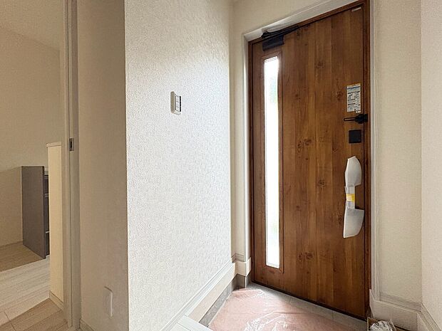 木目調の玄関ドアと室内側の玄関スペース