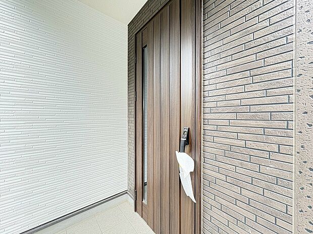 木目調の玄関ドアとタイル壁