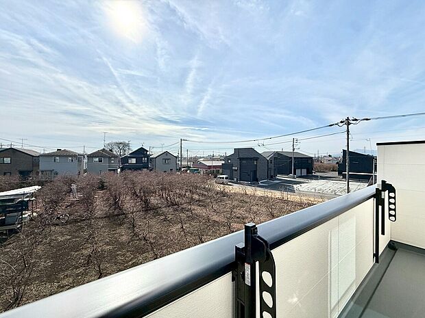 バルコニーから見える広い畑と遠くの住宅街の眺望