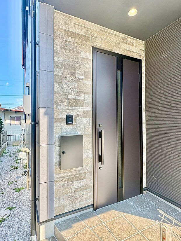 シンプルなデザインの玄関ドアと郵便受けがある入口部分