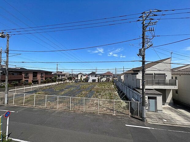 道路に面した更地と周辺住宅