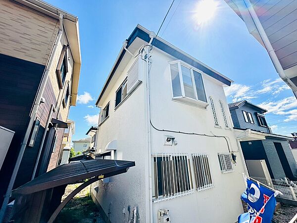 青空の下に建つ白い外壁の住宅
