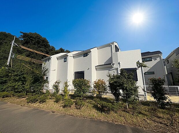 緑に囲まれた白い外壁の戸建て外観