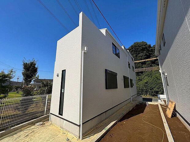 白い外壁の戸建て住宅と側面通路