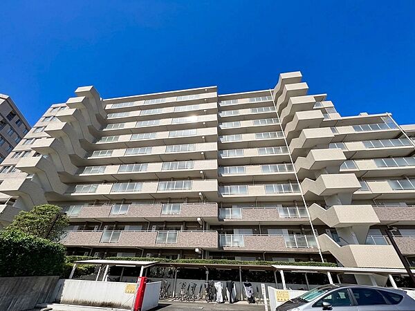 複数階のマンション外観、青空の下で撮影されています