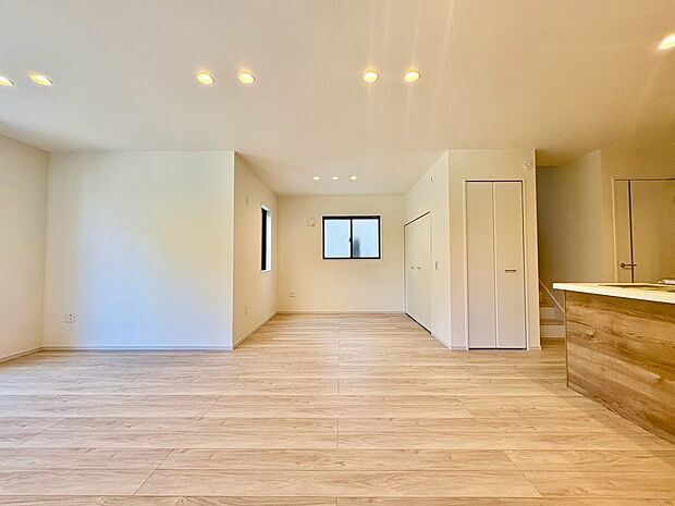 ナチュラルな床材のリビングと見えるキッチン
